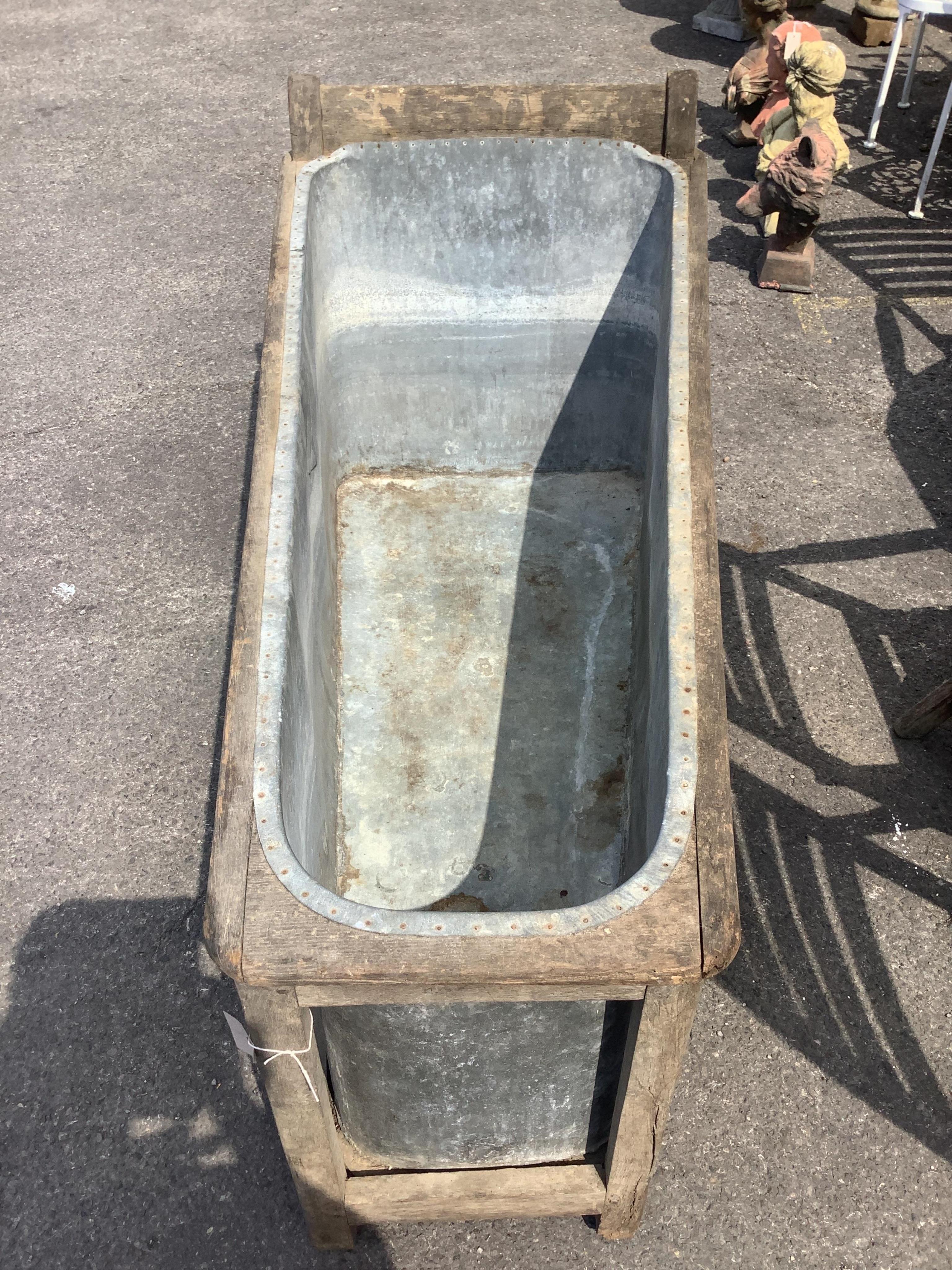 A 19th century French Provincial zinc lined bath with a wooden surround, length 153cm, height 74cm